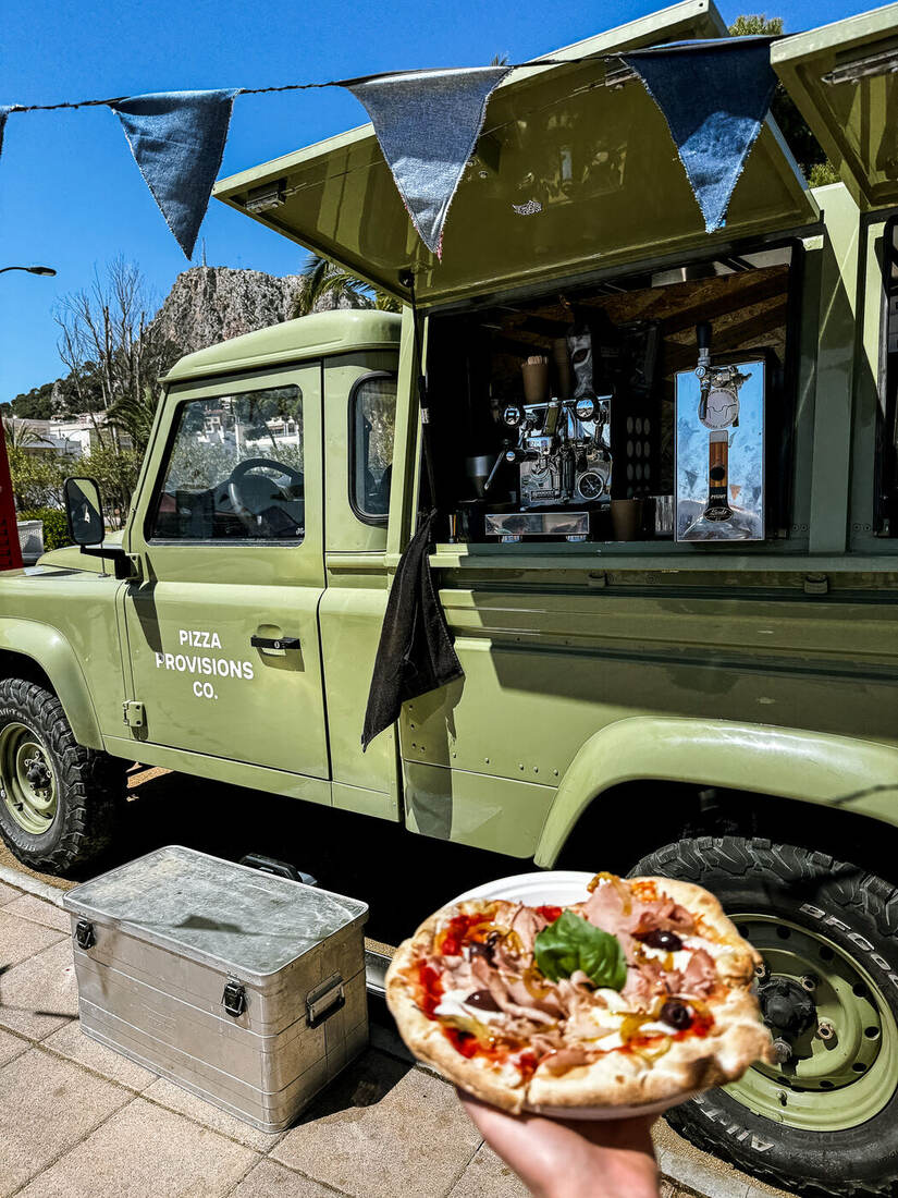 Camión de Pizza Provisions Co. sirviendo pizza con un paisaje de montaña de fondo